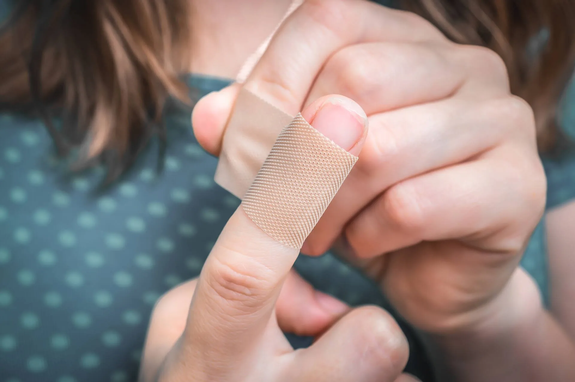 Woman with damaged nail, wrapping it up in a bandaid