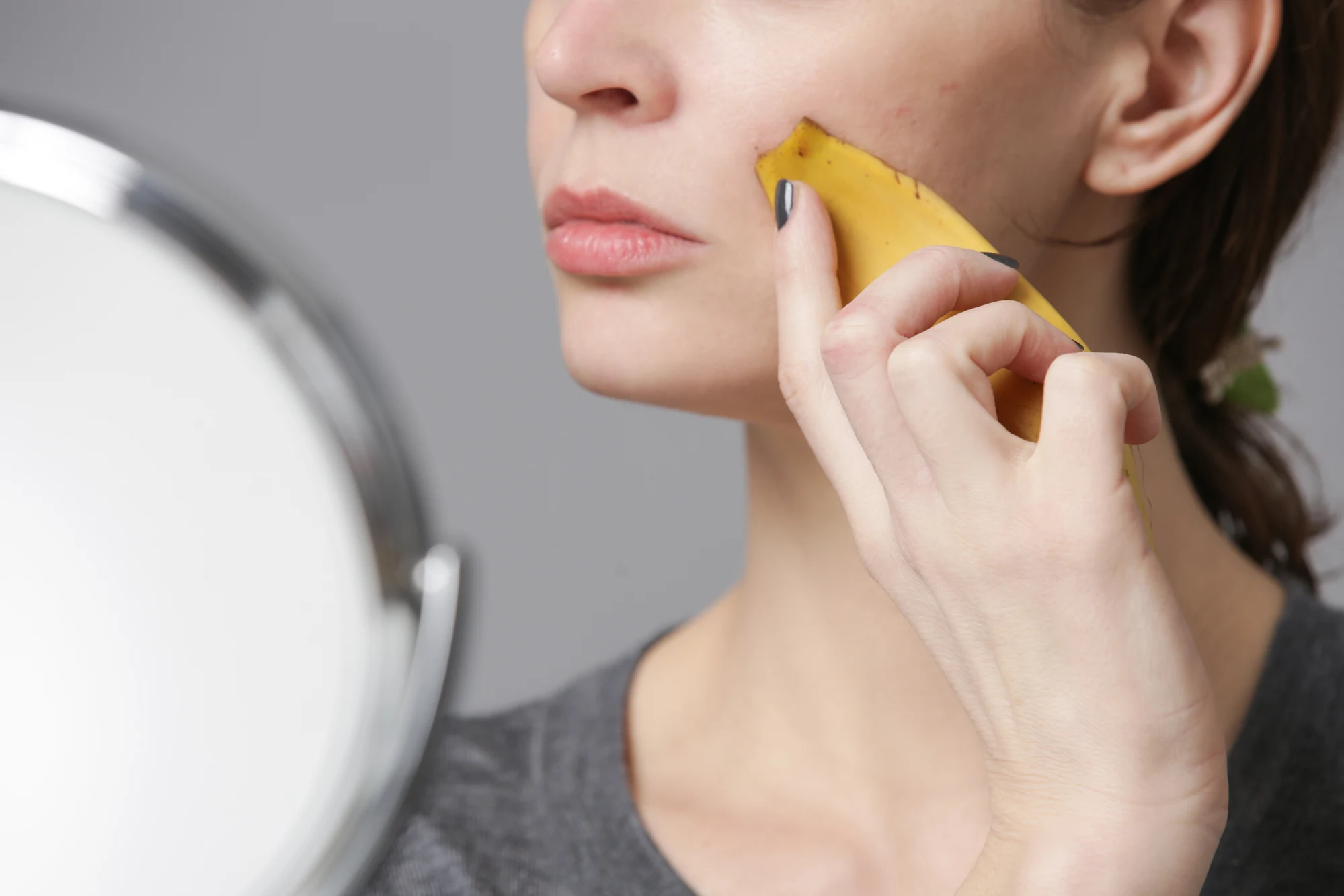 Brunette haired woman using a banana peel on her face for botox benefits
