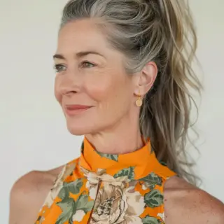This voluminous high ponytail combines sophistication and youthfulness. The hairstyle features a sleek top with a high, bouncy ponytail cascading in soft, loose waves. The lifted crown adds volume and height, giving a lively and rejuvenated look, making it ideal for an effortless, stylish appearance.